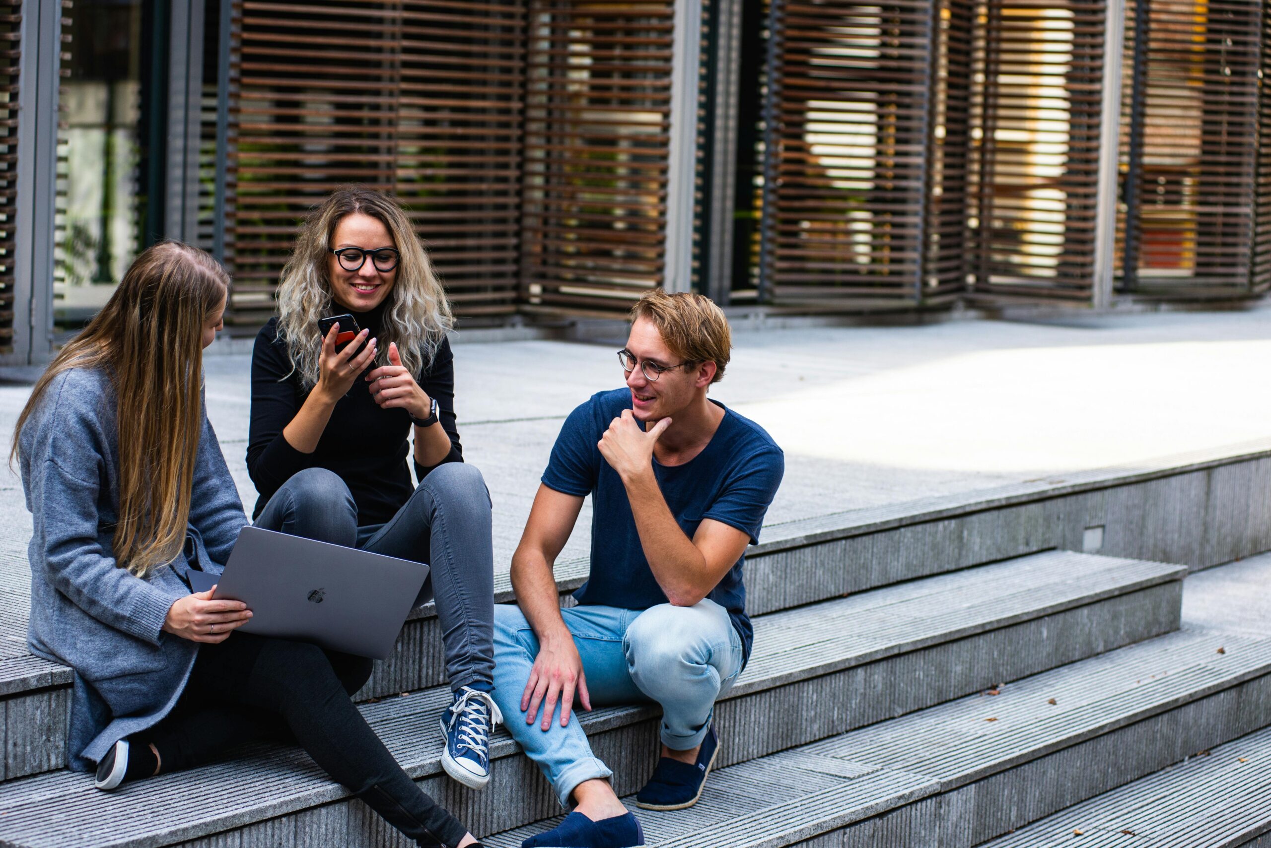 Three sales interns talking casually on the stairs