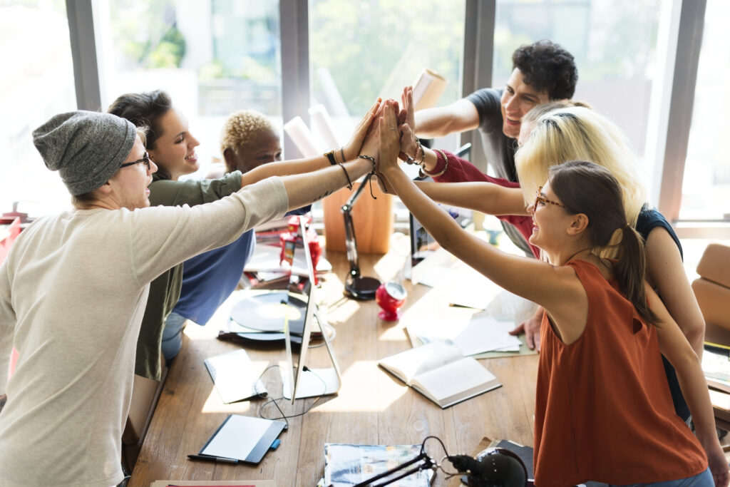 Diverse coworkers celebrating together in a creative office, showcasing strong team culture.